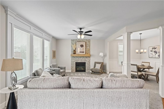 living room with a fireplace, carpet floors, and ceiling fan with notable chandelier