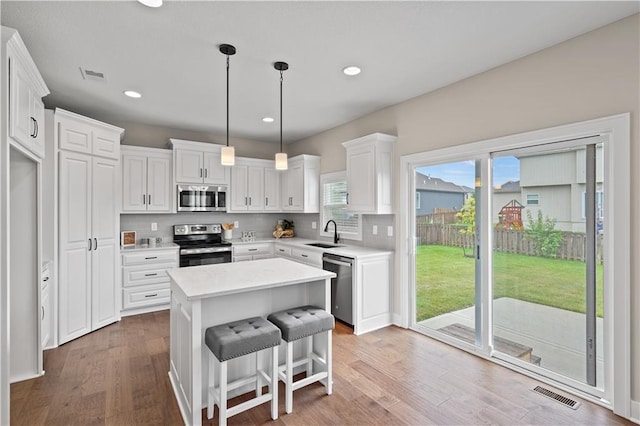 kitchen with white cabinetry, a center island, stainless steel appliances, and sink