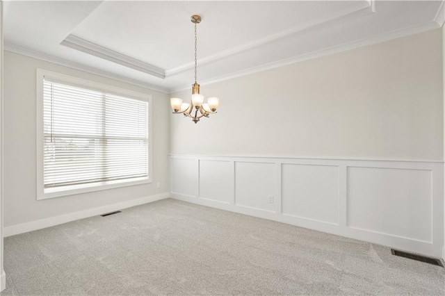 spare room with light carpet, a chandelier, a raised ceiling, and crown molding