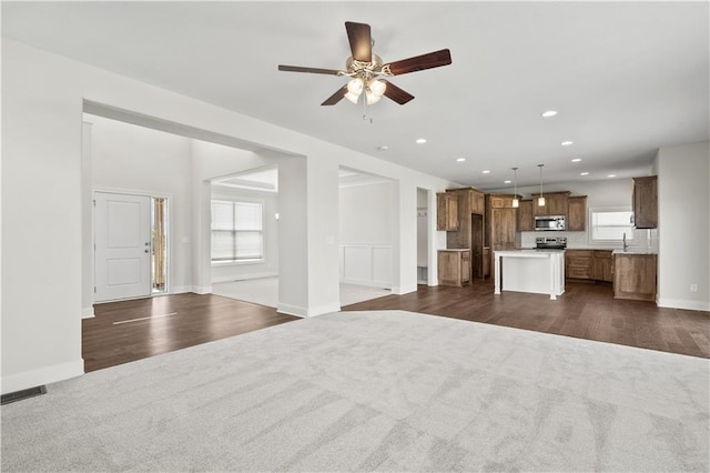 unfurnished living room featuring ceiling fan, sink, and dark wood-type flooring