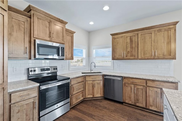 kitchen with sink, light stone countertops, stainless steel appliances, and dark wood-type flooring