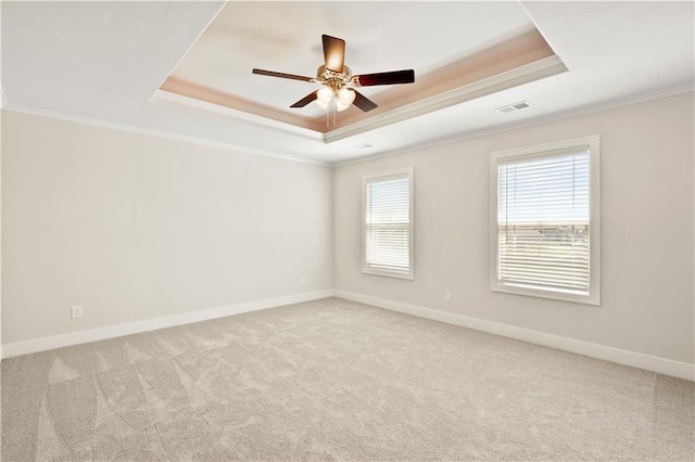 empty room featuring a tray ceiling, ceiling fan, crown molding, and light colored carpet