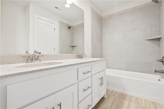 bathroom with tiled shower / bath combo and vanity