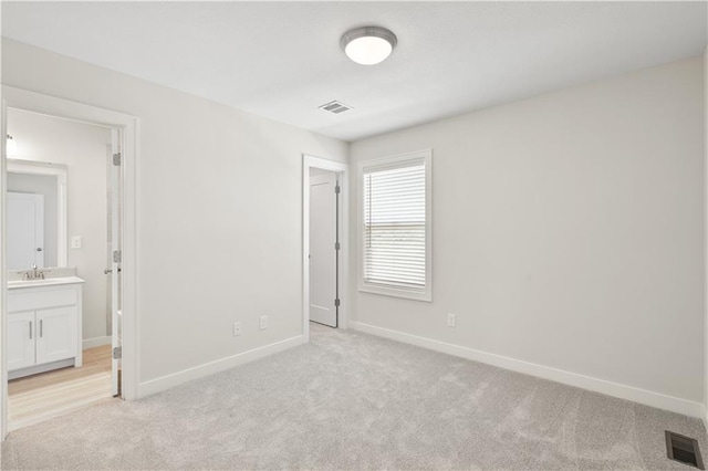 unfurnished bedroom with connected bathroom and light colored carpet