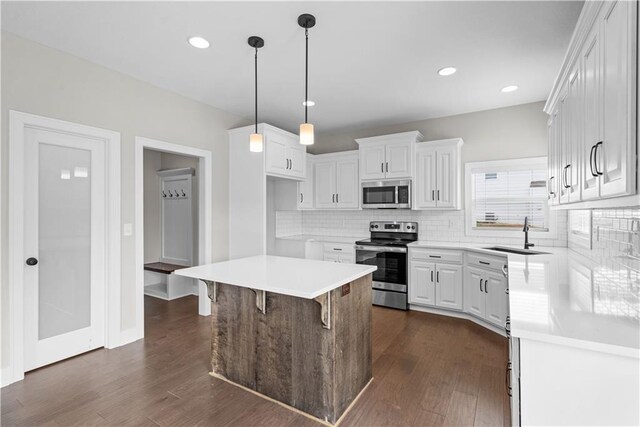 kitchen featuring dark hardwood / wood-style flooring, a kitchen island, stainless steel appliances, backsplash, and sink