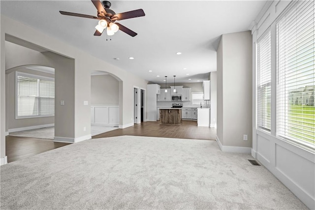 unfurnished living room with carpet flooring and ceiling fan