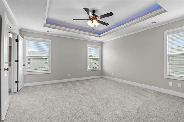 carpeted spare room featuring ornamental molding, ceiling fan, and a tray ceiling