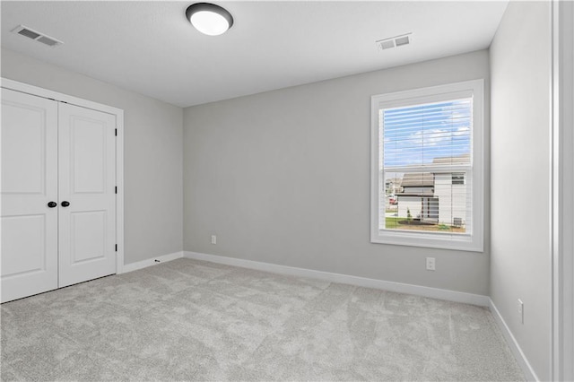 unfurnished bedroom featuring light carpet and a closet