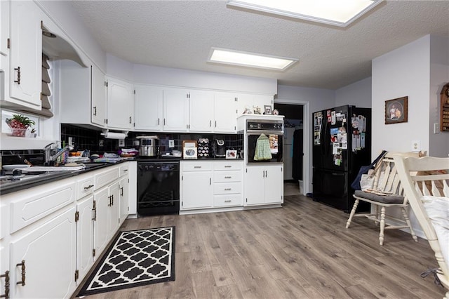 kitchen with black appliances, white cabinets, tasteful backsplash, and a textured ceiling