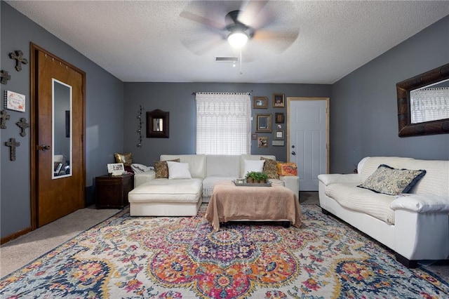 living room with carpet, ceiling fan, and a textured ceiling