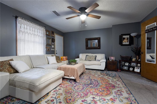 carpeted living room featuring ceiling fan and a textured ceiling