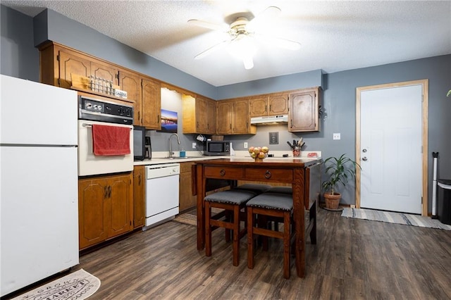 kitchen with dark wood-type flooring, sink, white appliances, and a textured ceiling