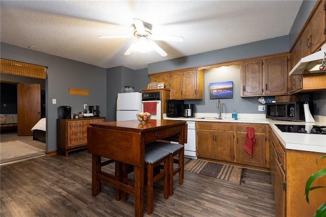 kitchen with dark wood-type flooring, sink, white appliances, and a textured ceiling