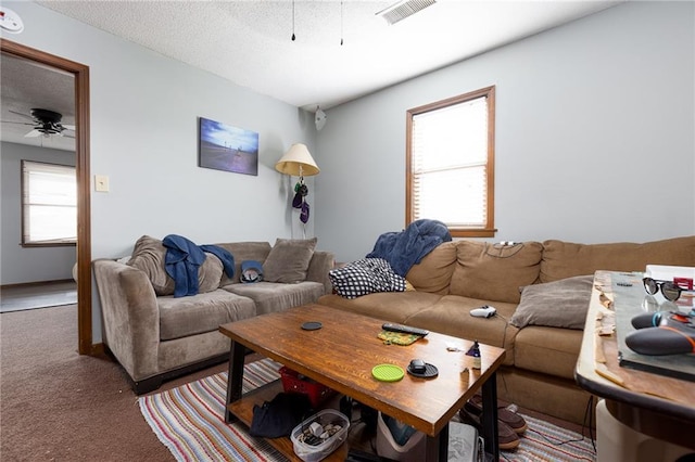 living room with ceiling fan, plenty of natural light, a textured ceiling, and carpet flooring