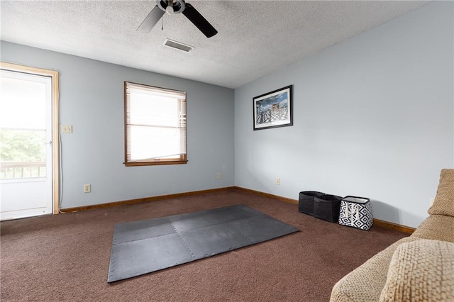 interior space with ceiling fan, dark carpet, and a textured ceiling