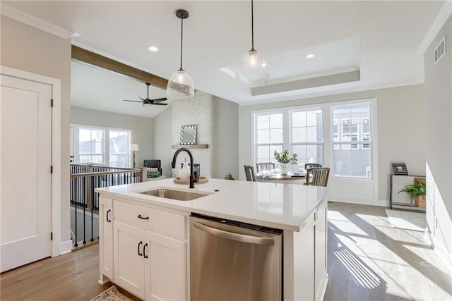 kitchen featuring pendant lighting, sink, dishwasher, white cabinets, and a center island with sink