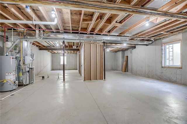 basement with a wealth of natural light, heating unit, and gas water heater