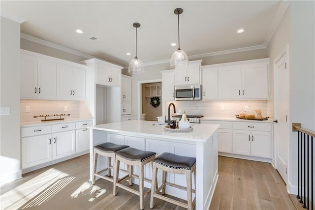 kitchen featuring a kitchen island with sink, sink, white cabinetry, and crown molding