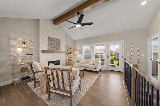 living room featuring a stone fireplace, ceiling fan, dark hardwood / wood-style flooring, and vaulted ceiling with beams