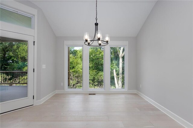 unfurnished dining area with light hardwood / wood-style flooring, lofted ceiling, and an inviting chandelier