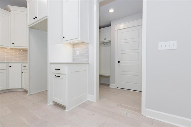 kitchen featuring decorative backsplash, white cabinets, and light hardwood / wood-style floors