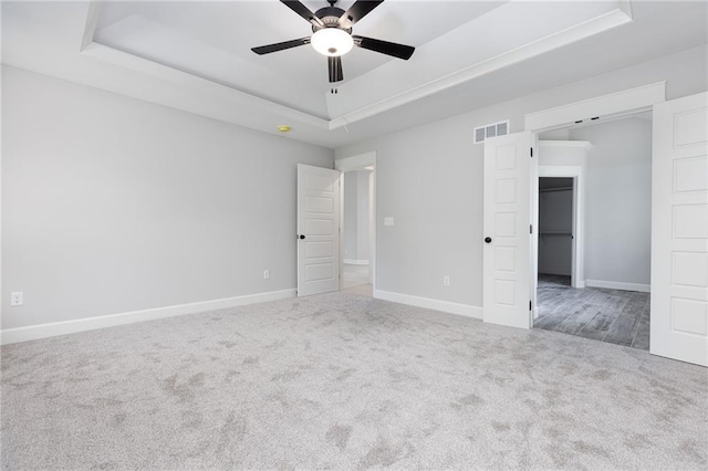 carpeted spare room featuring a tray ceiling and ceiling fan