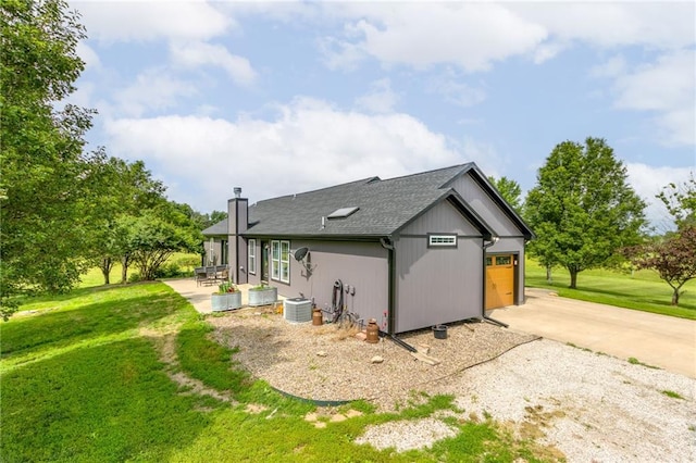 view of side of property featuring a lawn, a patio area, and a garage