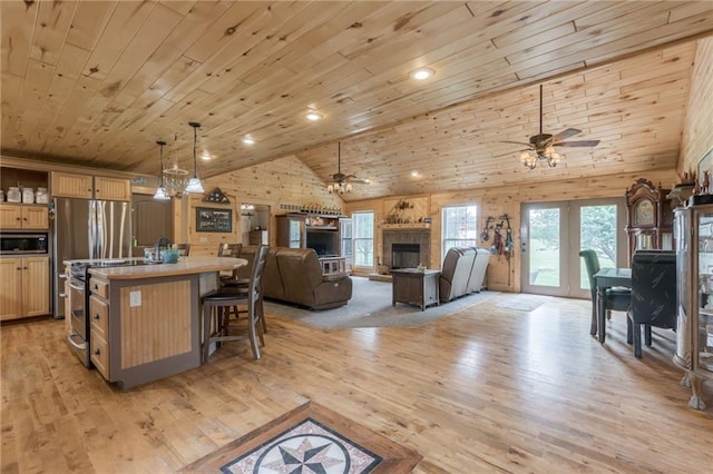 kitchen featuring stainless steel appliances, decorative light fixtures, wooden ceiling, light hardwood / wood-style floors, and an island with sink