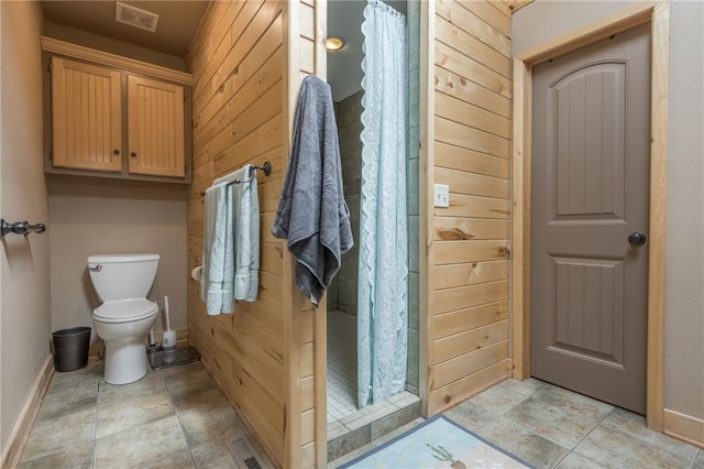 bathroom featuring wooden walls, toilet, and walk in shower