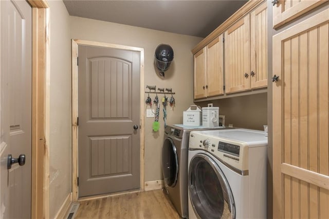 laundry room with cabinets, light hardwood / wood-style floors, and washer and clothes dryer