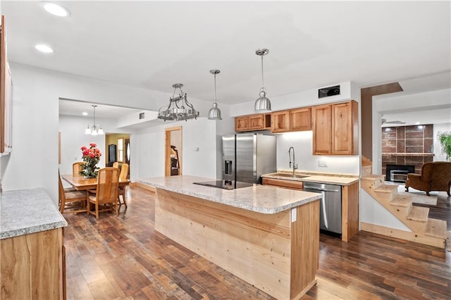 kitchen with sink, stainless steel appliances, dark hardwood / wood-style floors, light stone counters, and decorative light fixtures