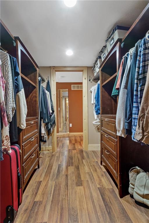 walk in closet with light hardwood / wood-style flooring