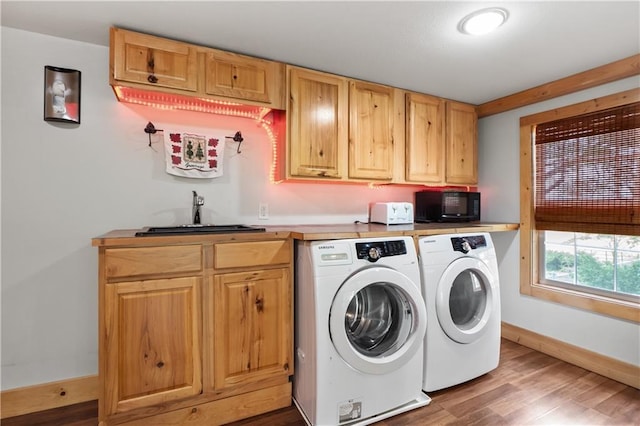 washroom featuring washing machine and clothes dryer, wood-type flooring, and sink