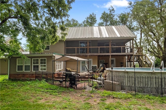 rear view of property with a fenced in pool, a sunroom, and a patio