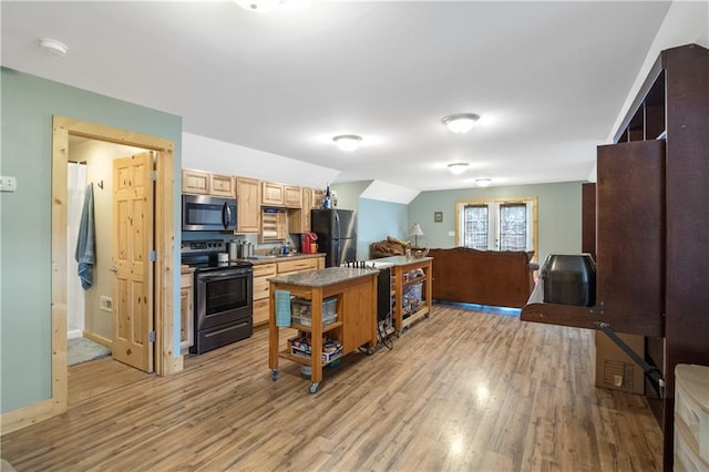 kitchen with stainless steel appliances, vaulted ceiling, a kitchen island, and light wood-type flooring