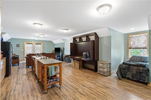 kitchen with black refrigerator, plenty of natural light, a center island, and light hardwood / wood-style flooring