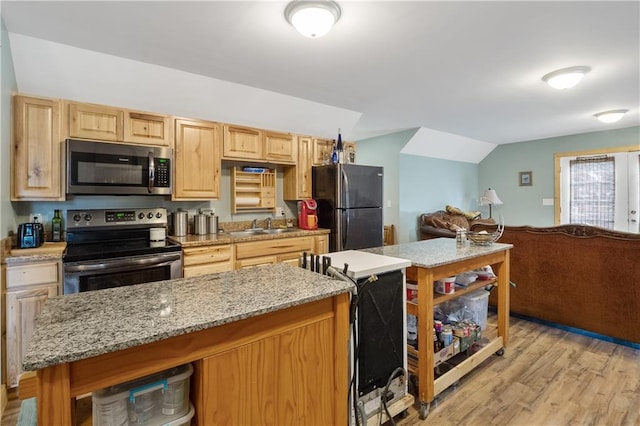 kitchen featuring vaulted ceiling, sink, light stone counters, light hardwood / wood-style floors, and stainless steel appliances