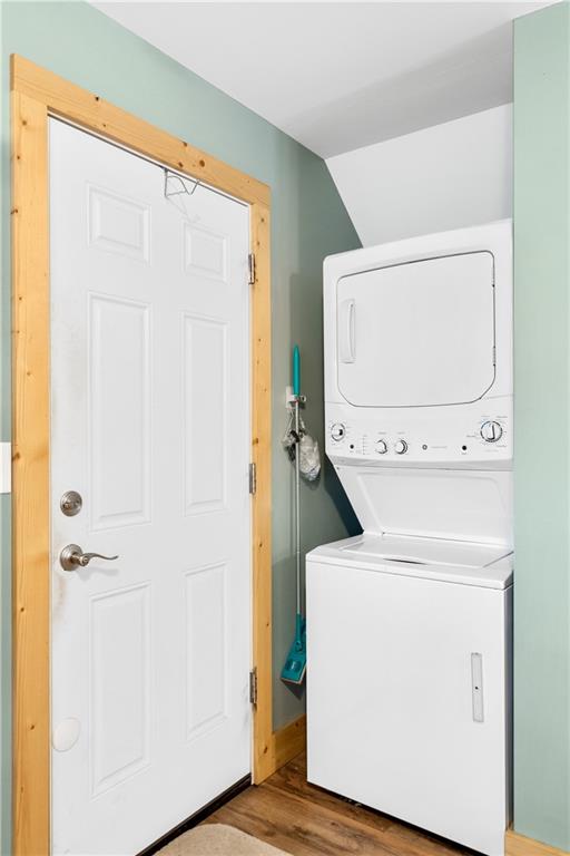 laundry area featuring stacked washer / drying machine and light wood-type flooring