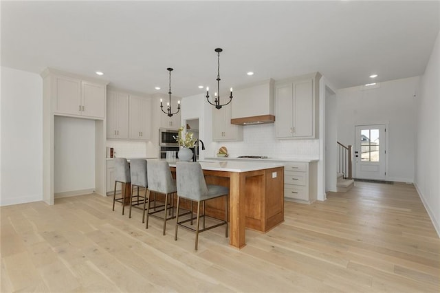 kitchen with white cabinetry, a large island, stainless steel appliances, and premium range hood