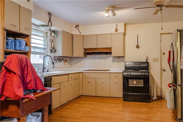 kitchen featuring sink, light hardwood / wood-style flooring, stainless steel refrigerator, black gas stove, and decorative backsplash