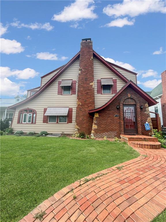 view of front of house with a chimney, a front lawn, and brick siding