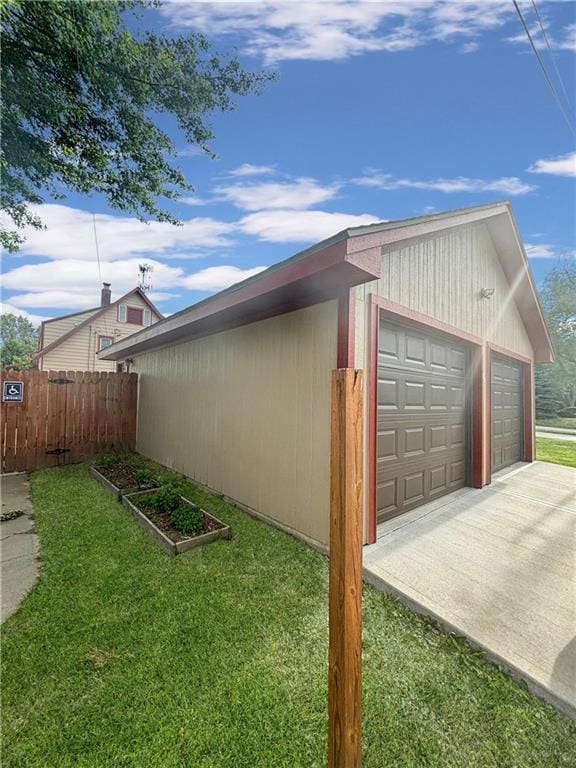 view of home's exterior with a detached garage, fence, a lawn, and an outbuilding