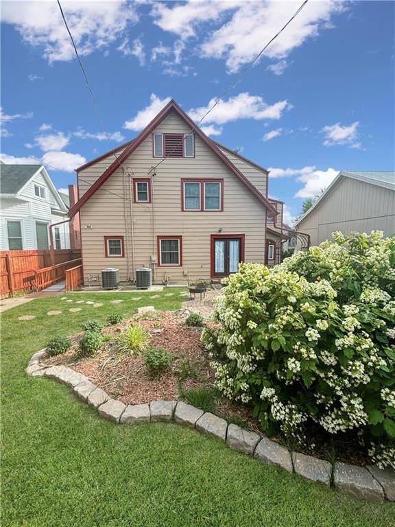 back of property featuring central AC unit and a yard