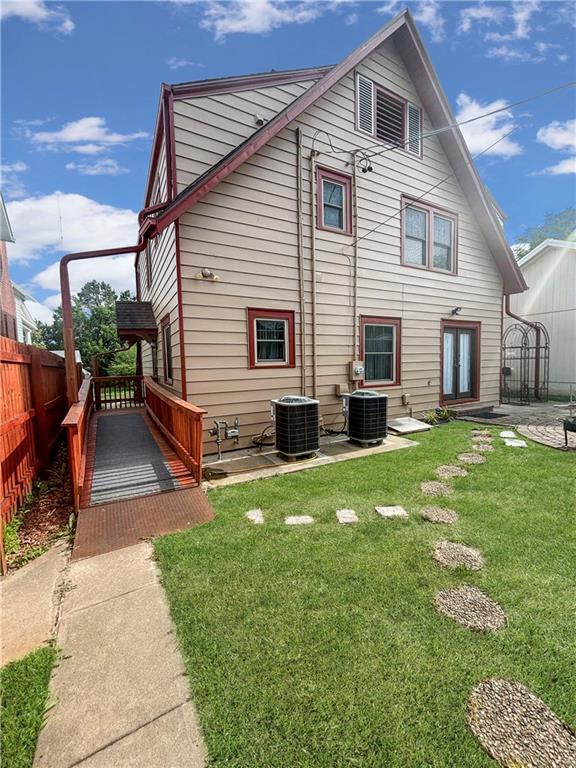 rear view of property with central AC unit and a yard