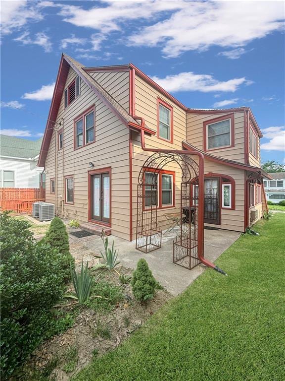 rear view of property with a lawn, fence, french doors, a patio area, and central AC