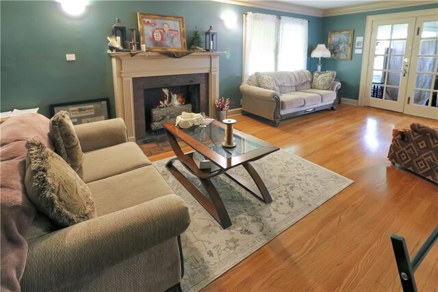 living room featuring a healthy amount of sunlight, a tile fireplace, hardwood / wood-style floors, and french doors