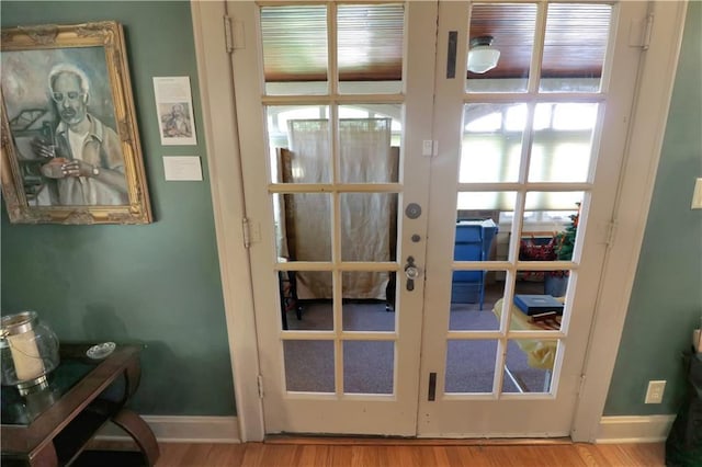 doorway to outside featuring baseboards, wood finished floors, and french doors