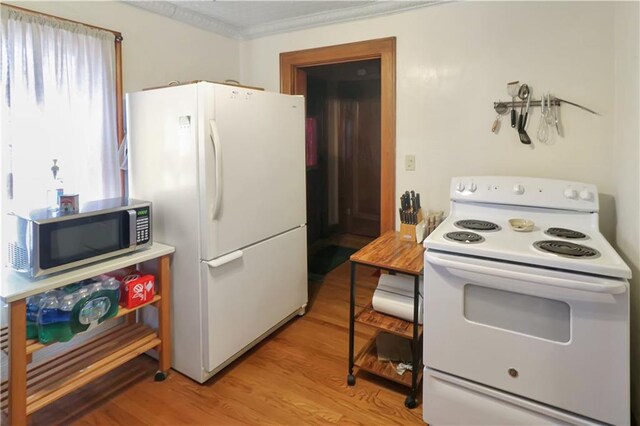 kitchen featuring ornamental molding, light wood-type flooring, and white appliances