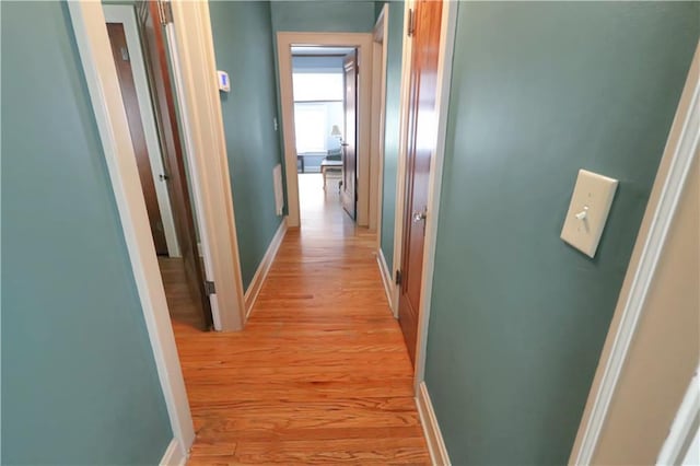 hallway with light wood-type flooring and baseboards