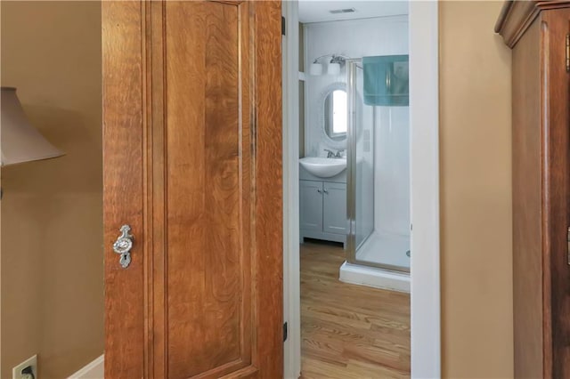 interior space with walk in shower, hardwood / wood-style flooring, and vanity